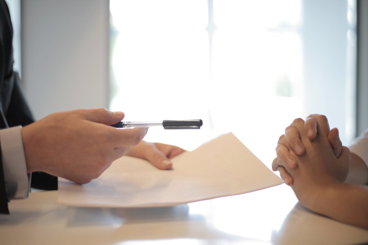 hero-img Close-up of a contract signing with hands over documents. Professional business interaction.