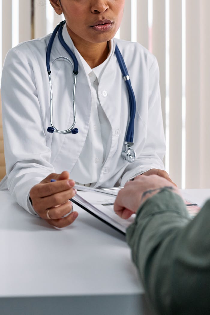 services-03 A doctor in a white coat consulting a patient at a table with medical documents.
